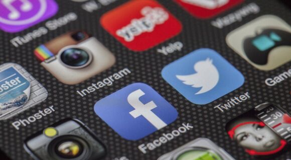 Der Bildschirm eines Smartphones zeigt mehrere Reihen von Symbolen für Social-Media-Plattformen, darunter Facebook, YouTube und Instagram.