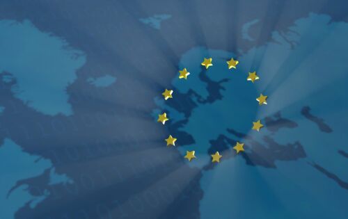 Zwölf goldene Sterne bilden einen Kreis - das Symbol der Europäischen Union. Dahinter sind die Konturen einer verwaschenen Landkarte zu erkennen. Der Sternenkreis liegt geographisch über Europa.